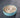 ceramic dog bowl with blue rim and beige center on a light gray background